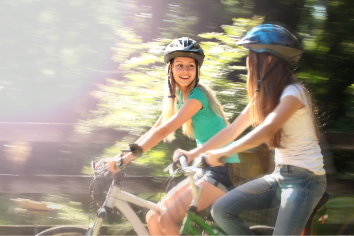 Two girls riding e-bikes wearing helmets