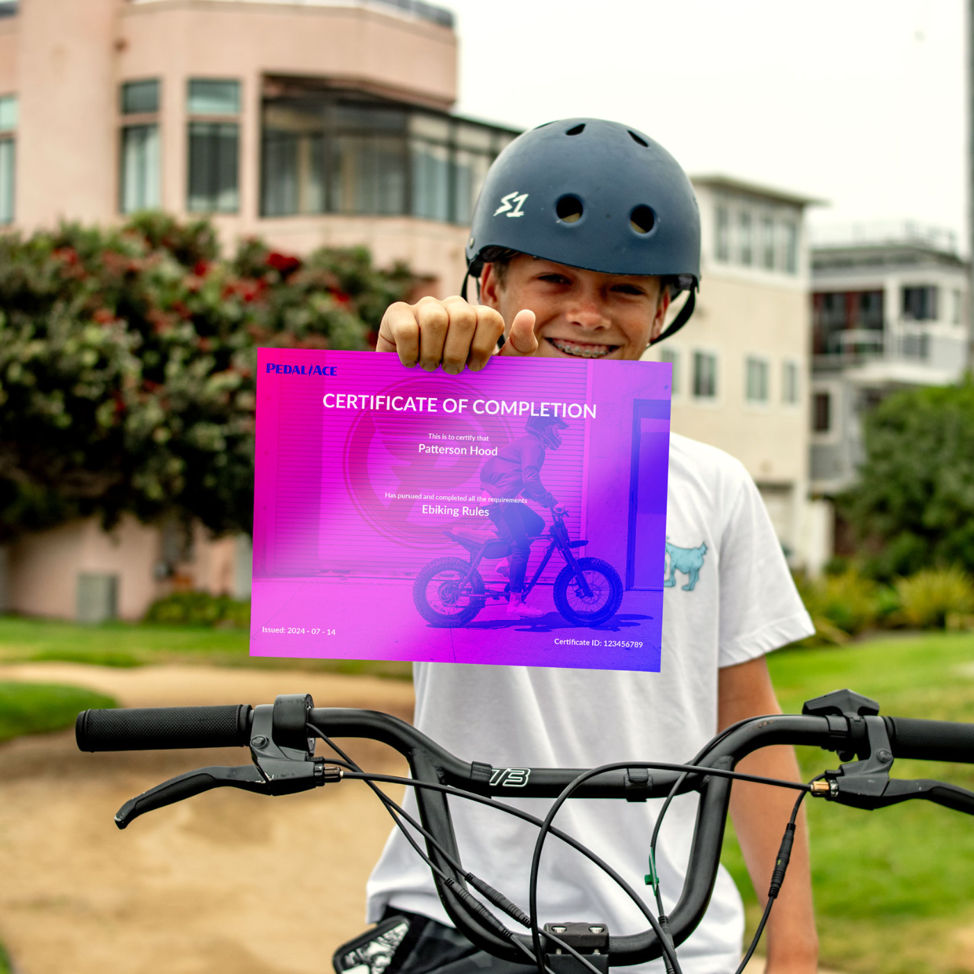 Child with a bicycle helmet holding a certificate of completion outdoors.