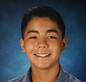 Young boy smiling against a blue background