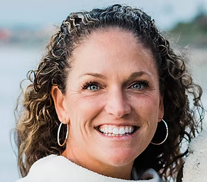 Woman with curly hair smiling outdoors with a blurred background